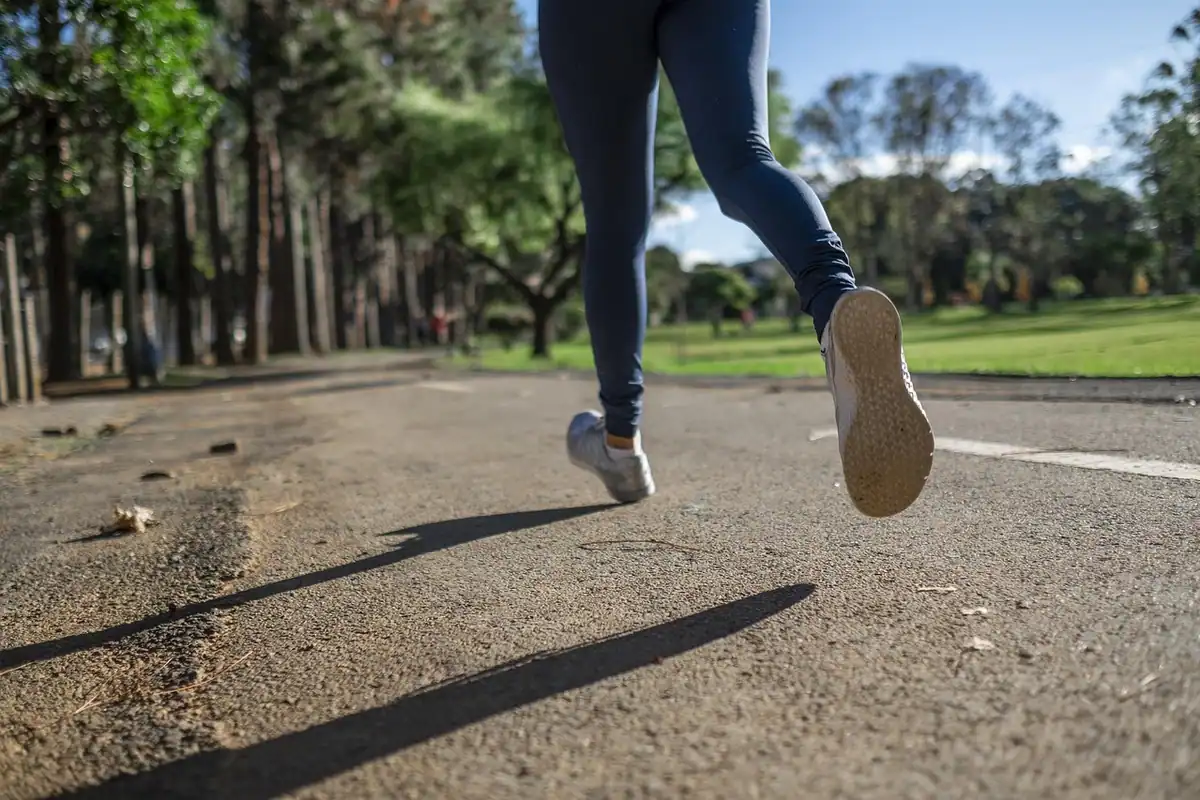 Picioarele unei alergătoare în pantofi sport pe o alee asfaltată din parc