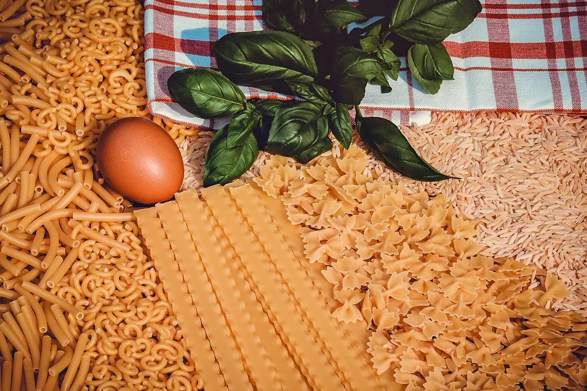 Farfurie cu paste și ingrediente simple pe masa din bucătărie, masă bogată în carbohidrați după efort