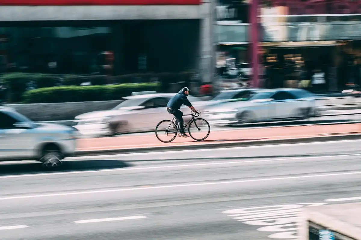 Biciclist care circulă pe un bulevard aglomerat, printre mașini în mișcare