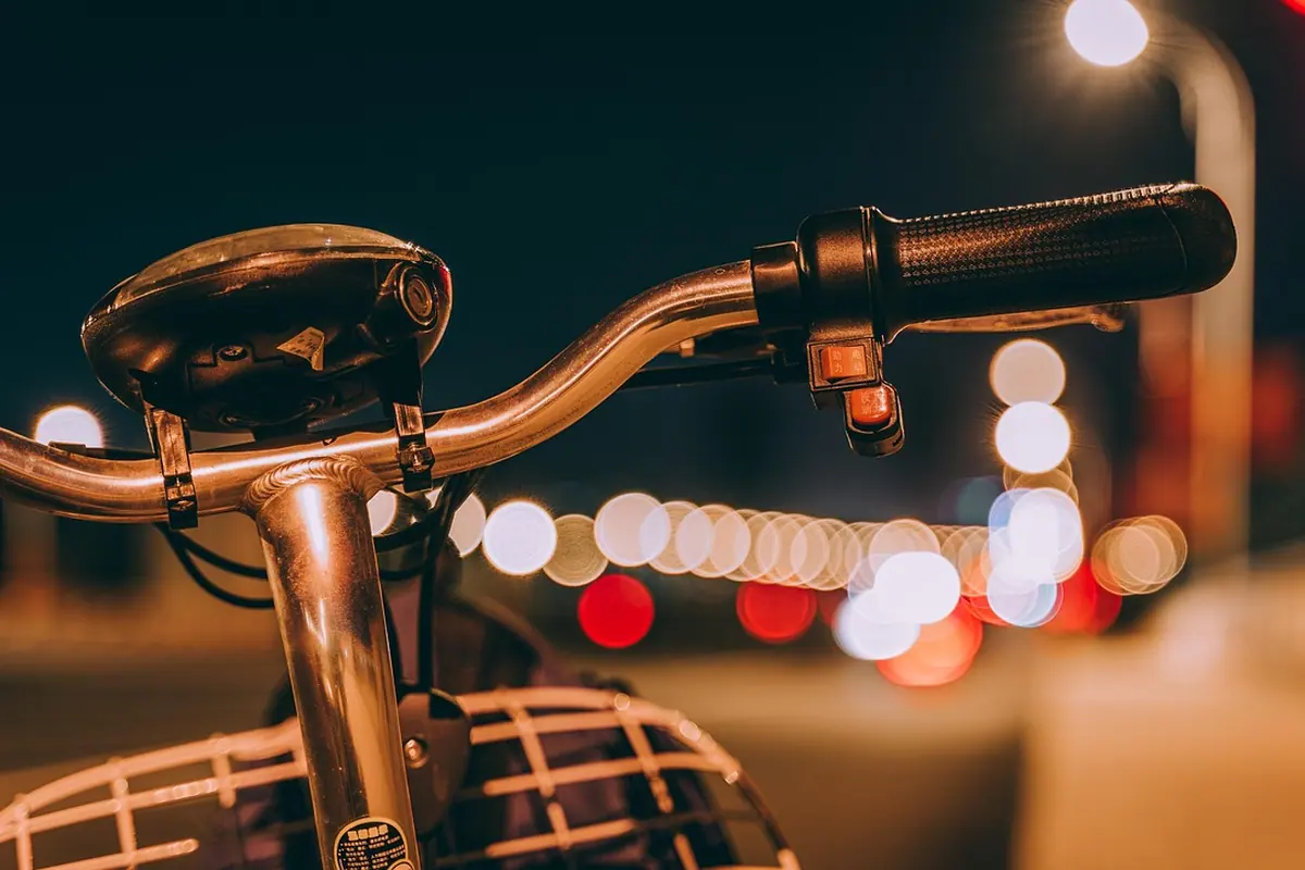 Ghidonul unei biciclete de oraș seara, cu luminile străzii în fundal