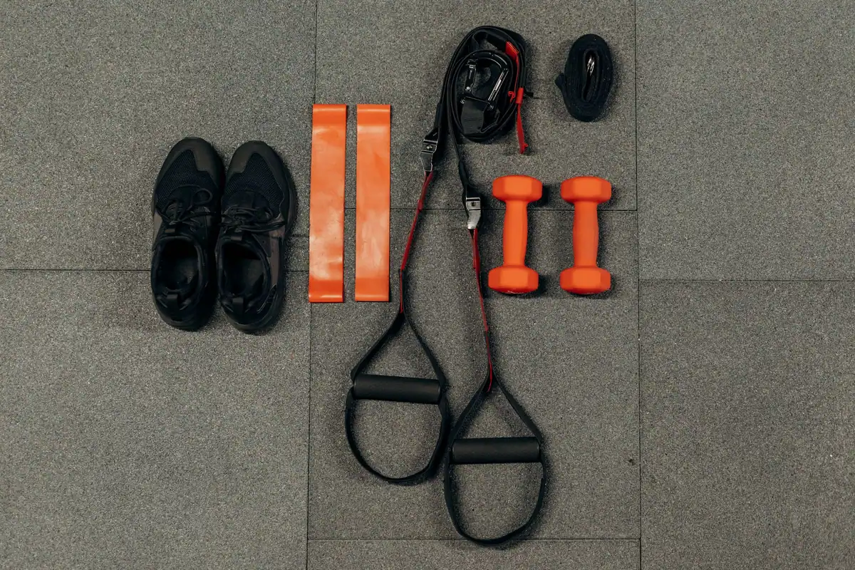 Pantofi sport, benzi elastice și curele de antrenament așezate pe podea