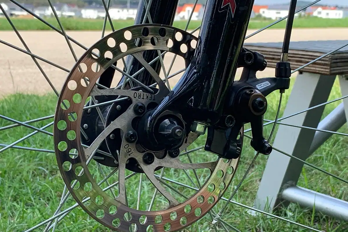 Disc de frână și etrier pe roata unei biciclete de munte, văzute de aproape