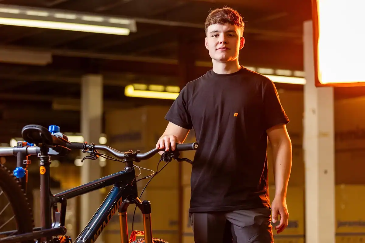 Tânăr lângă bicicleta sa într-un atelier, pregătită pentru revizie