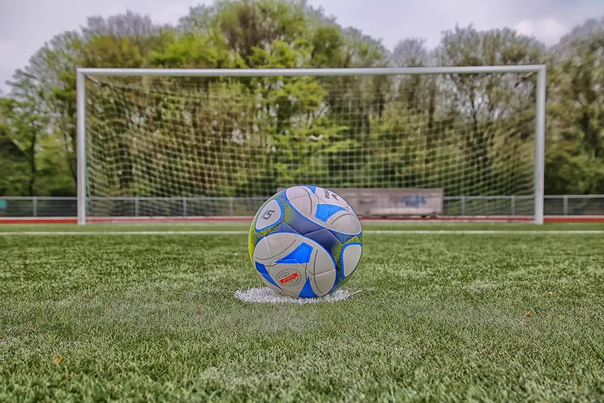 Minge de fotbal pe punctul de la 11 metri, pe iarba unui teren, pregătită pentru lovitura de pedeapsă