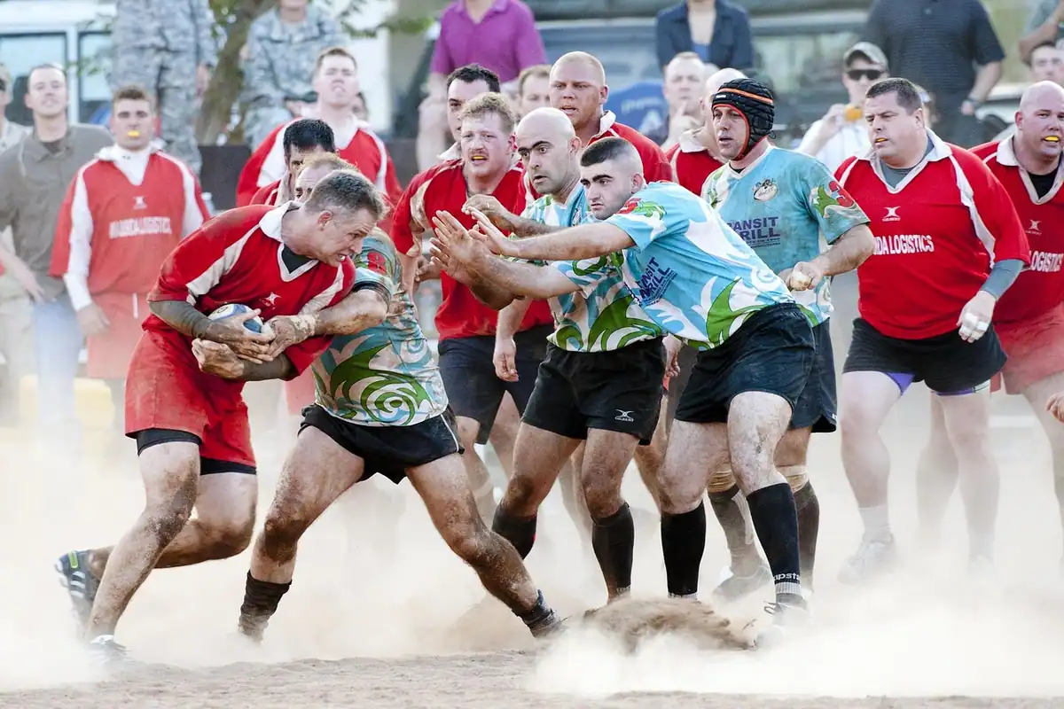 Jucători de rugby care se luptă pentru minge pe un teren prăfuit