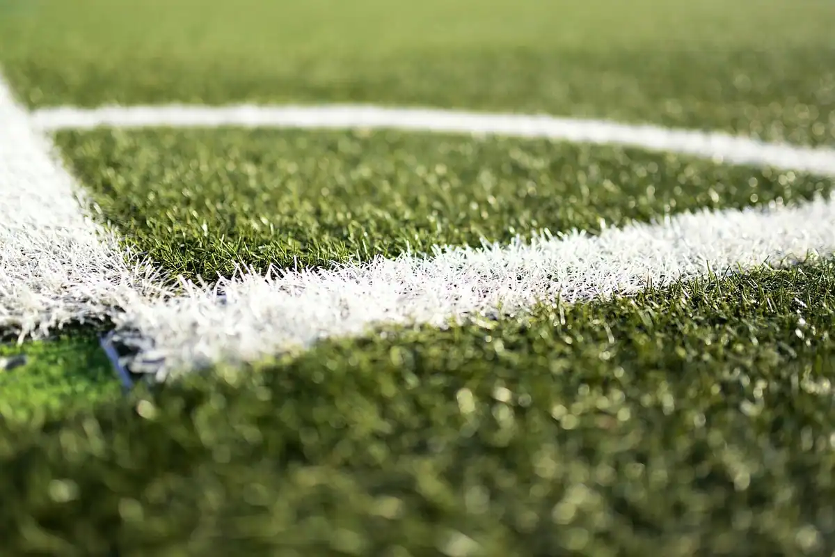 Colțul unui teren de fotbal cu gazon artificial și linii albe