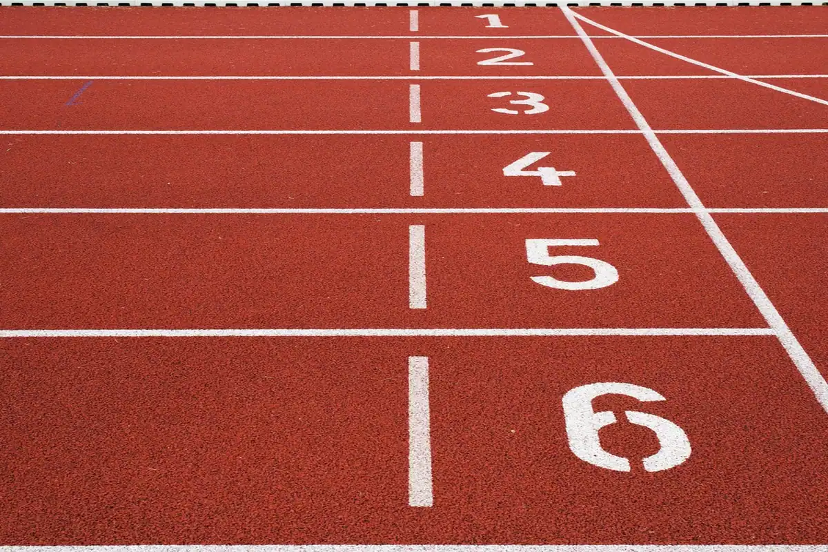 Linii albe și numere de culoar pe o pistă de atletism roșie