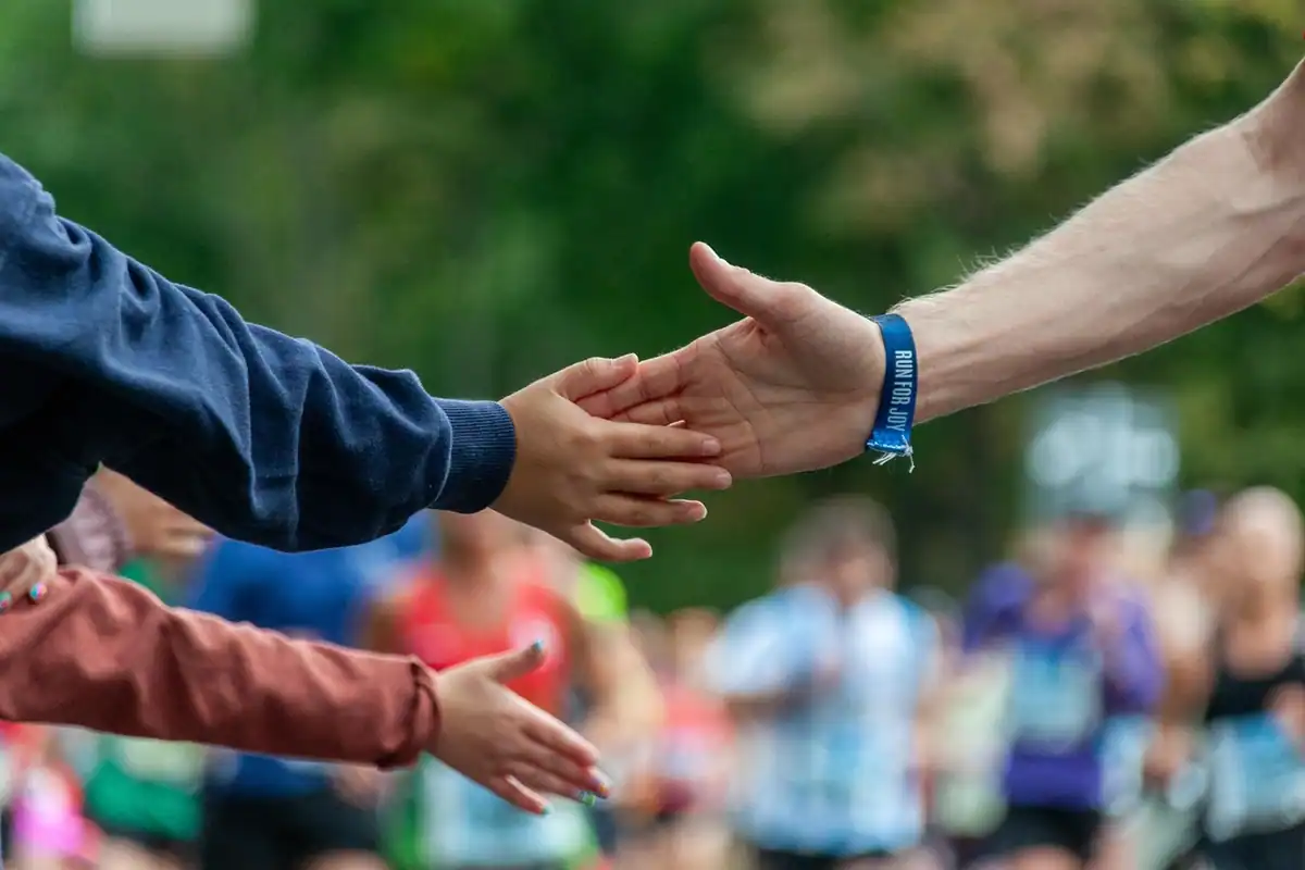 Spectatori care bat palma cu alergătorii pe traseul unui semimaraton