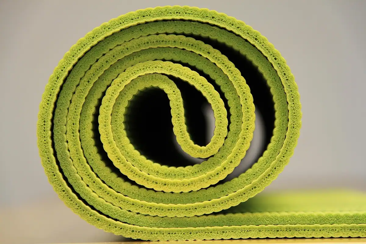 Saltea de yoga verde întinsă pe podea, pentru exerciții de relaxare