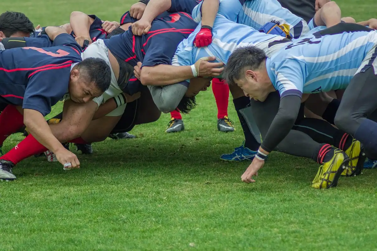 Jucători de rugby legați într-o grămadă ordonată pe gazon