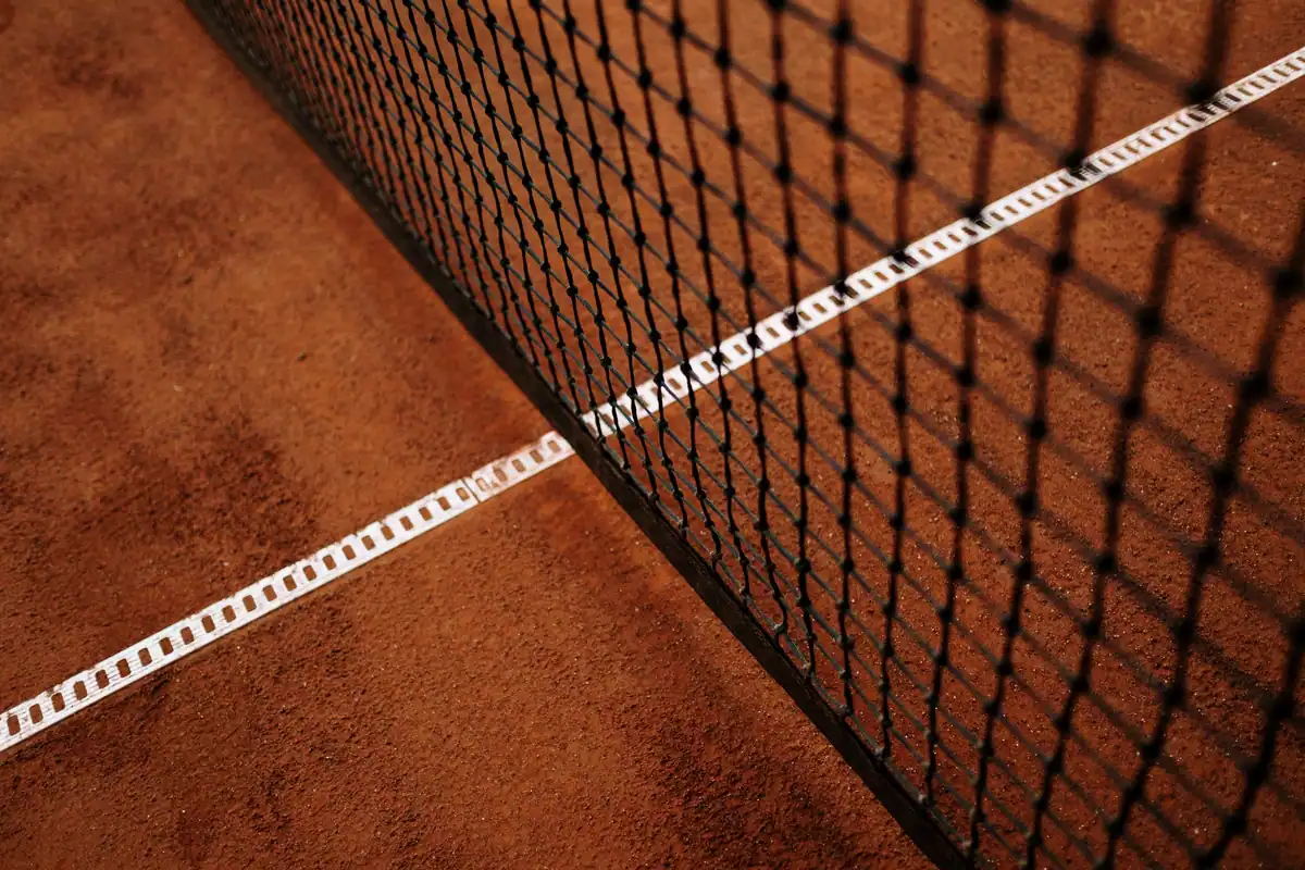 Plasa și linia albă de fund pe un teren de tenis din zgură, văzute de aproape