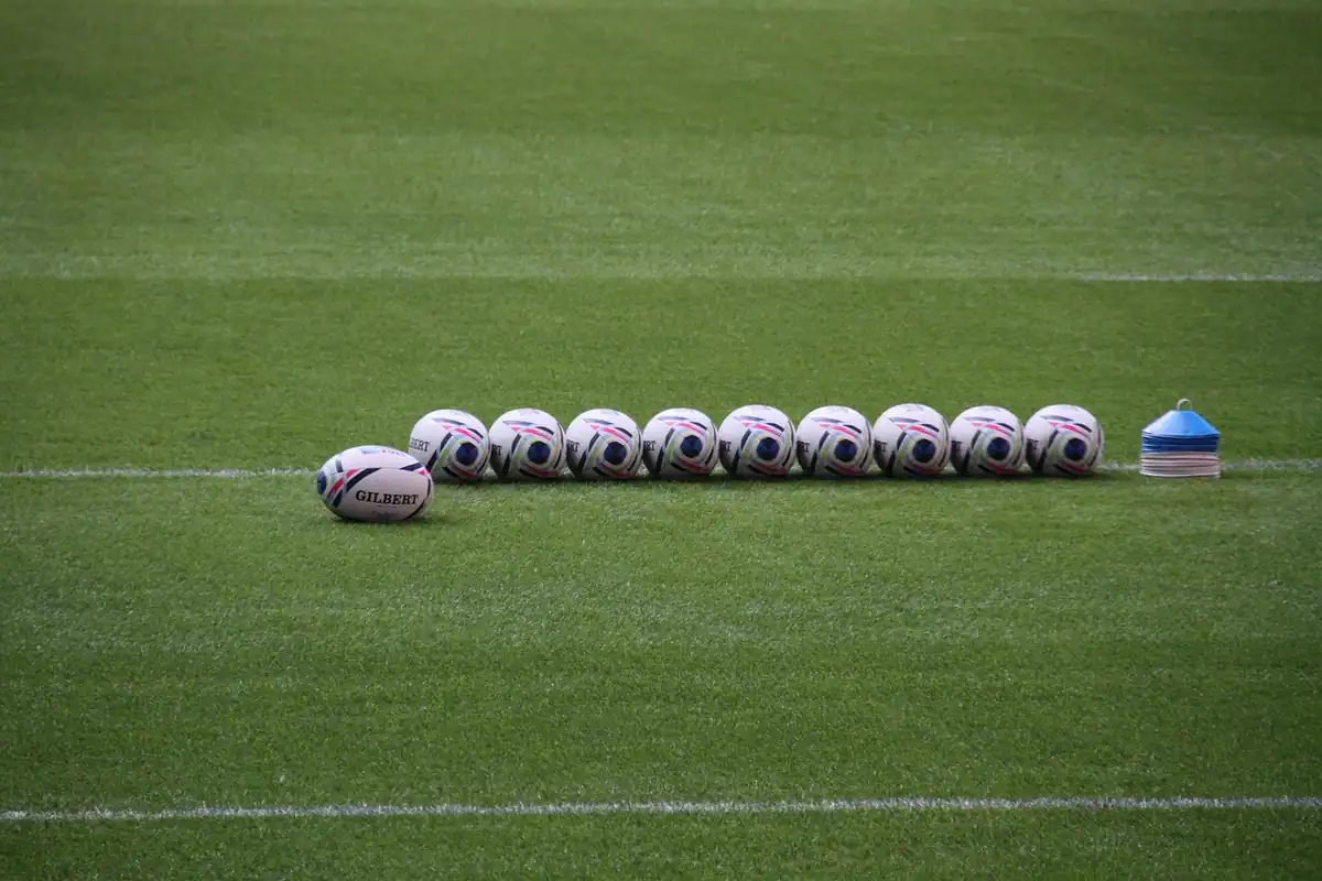 Porți de rugby în formă de H la apus, pe un teren de joc, cu cerul colorat în fundal