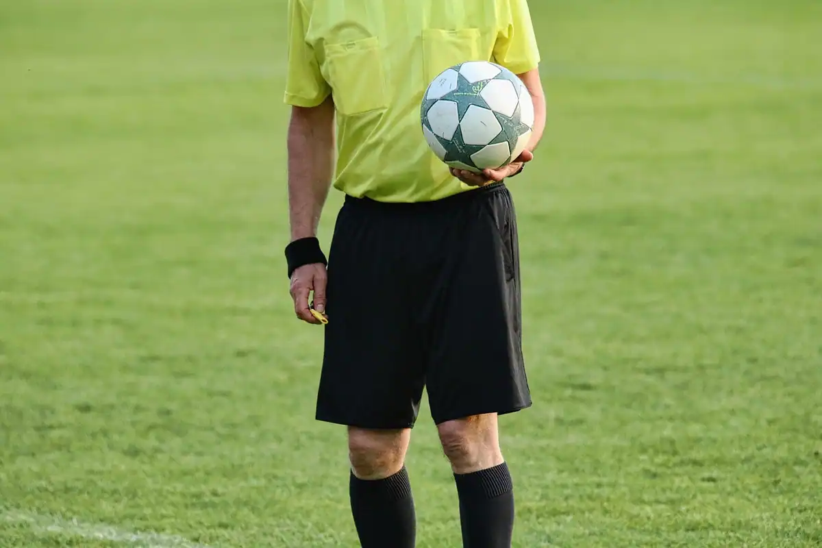 Arbitru de fotbal care ține mingea în mână pe marginea terenului
